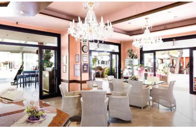 een eetkamer met witte stoelen en tafels en kroonluchters bij HOTEL D'ANNUNZIO in Lido di Jesolo