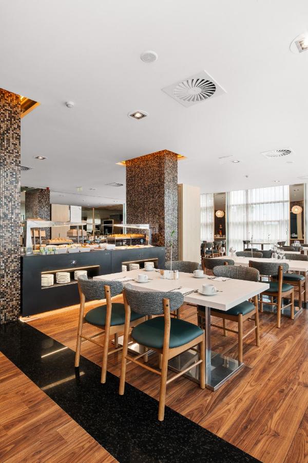 een eetzaal met tafels en stoelen in een restaurant bij Axis Porto Business & Spa Hotel in Porto +40 foto's