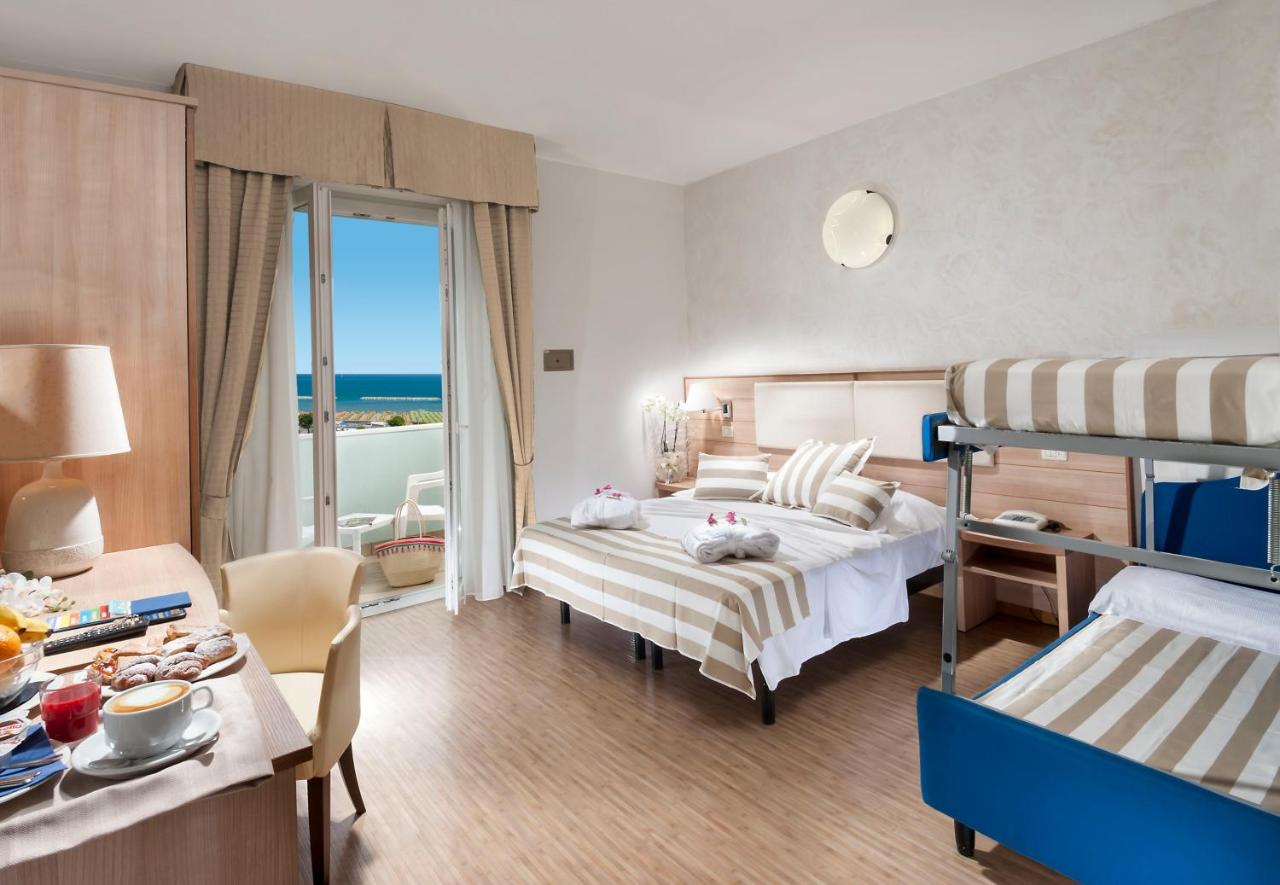 een hotelkamer met twee bedden, een tafel en een eetkamer bij Hotel Losanna in Gabicce Mare