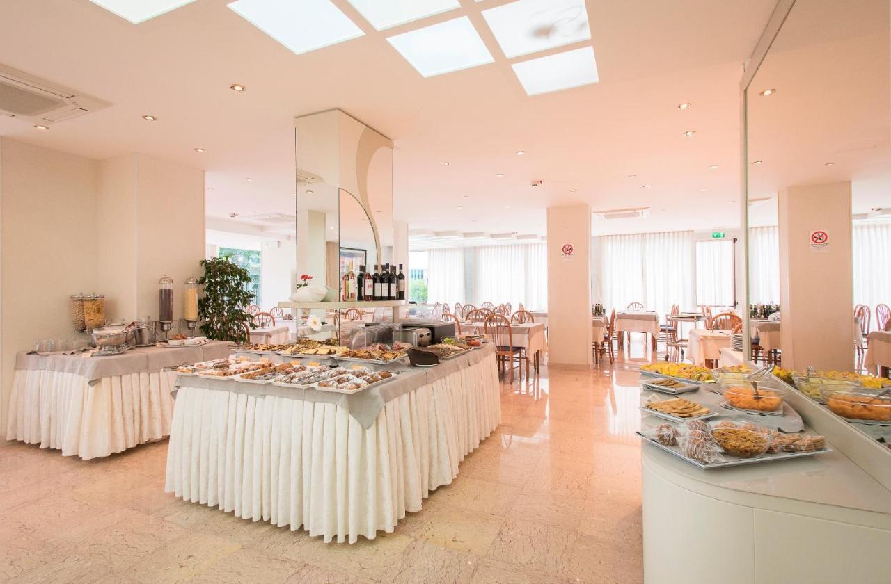 een grote ruimte met tafels waarop eten wordt uitgestald bij Hotel Losanna in Gabicce Mare