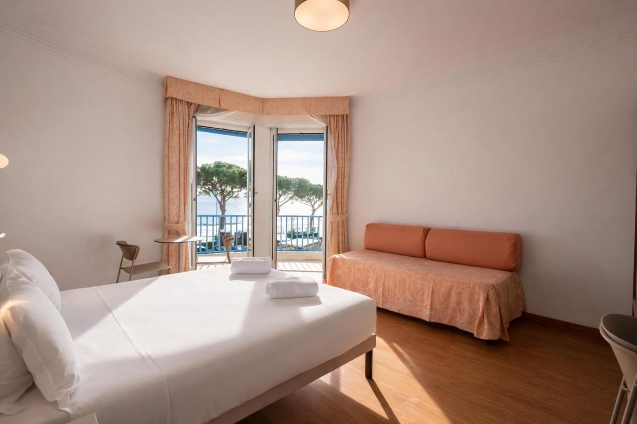 een slaapkamer met een bed, een bank en een raam bij LVG Hotel Collection - Majestic in Alassio