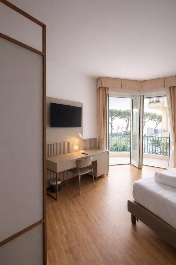 een slaapkamer met een bed, een bureau en een televisie bij LVG Hotel Collection - Majestic in Alassio