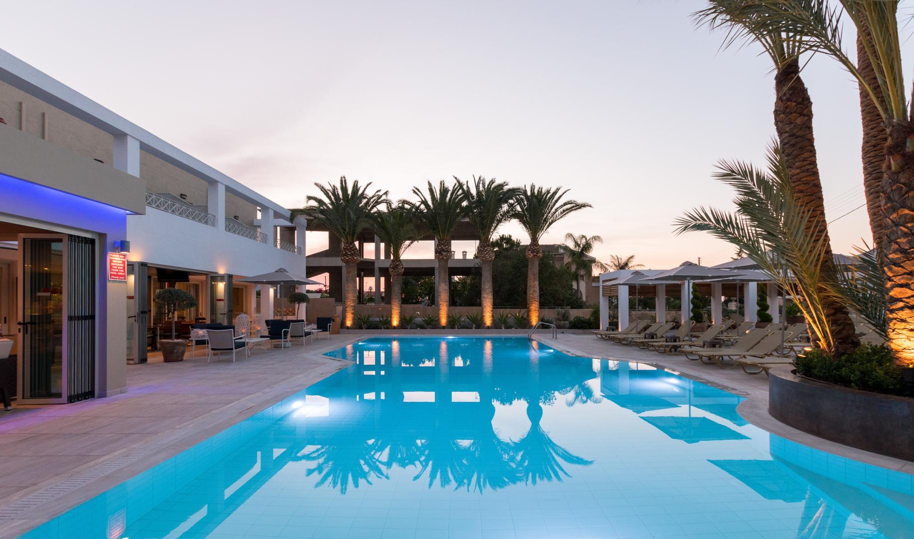 Zwembad omringd door palmbomen — Dedalos Hotel