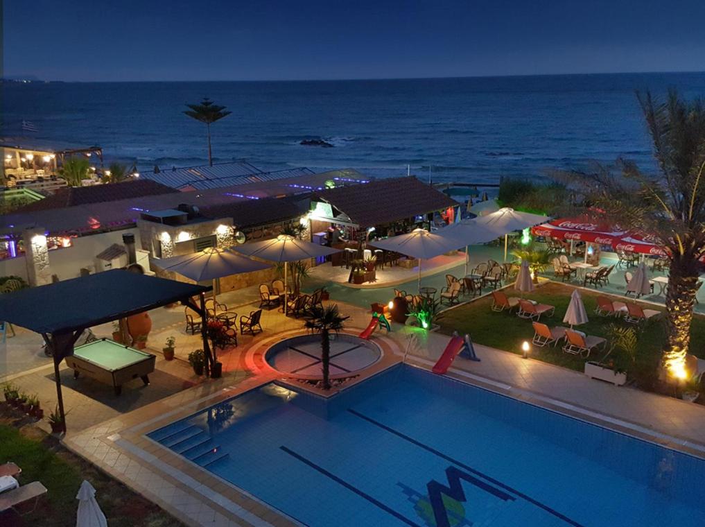 een bovenaanzicht van een zwembad en de oceaan 's nachts bij Malliotakis Beach Hotel "by Checkin" in Stalida