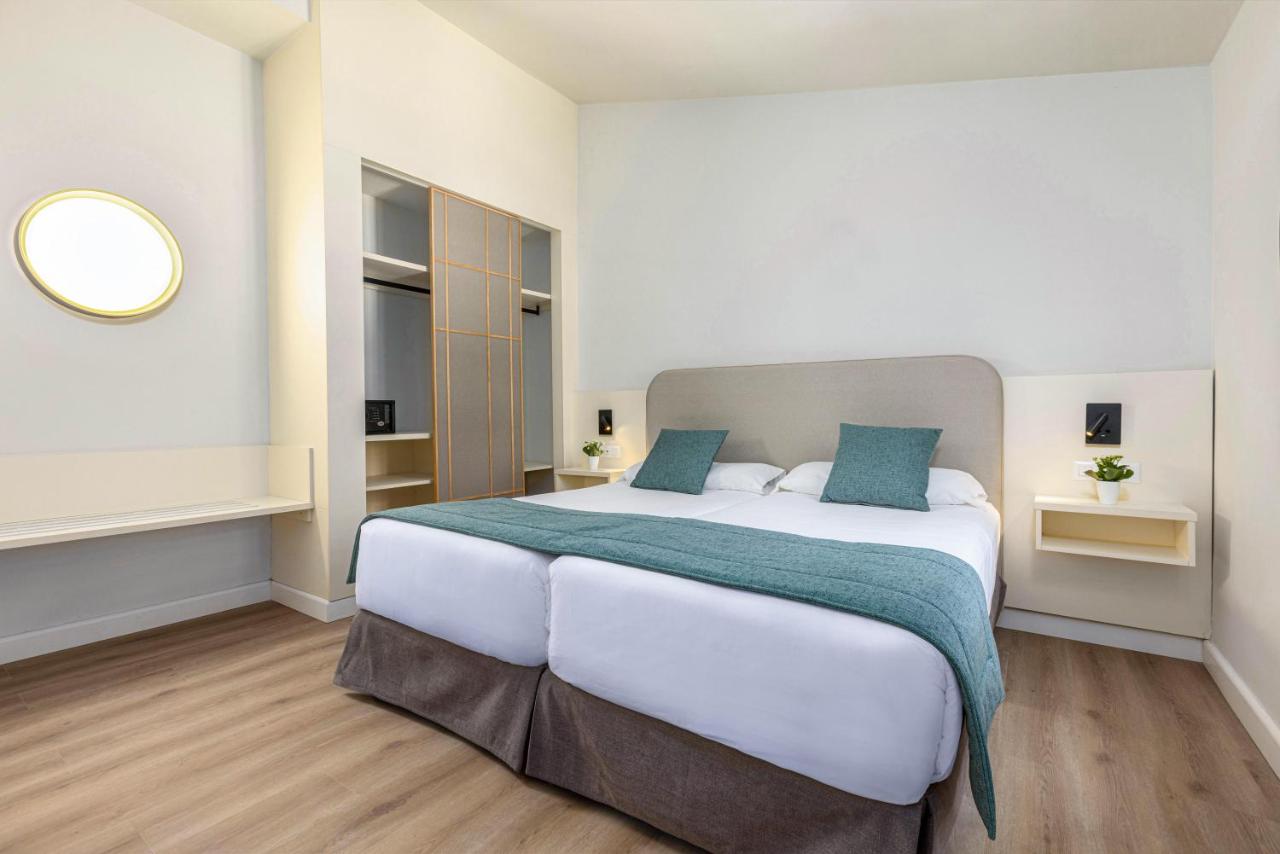 een slaapkamer met een groot wit bed met blauwe kussens bij Maspalomas Resort by Dunas in Maspalomas