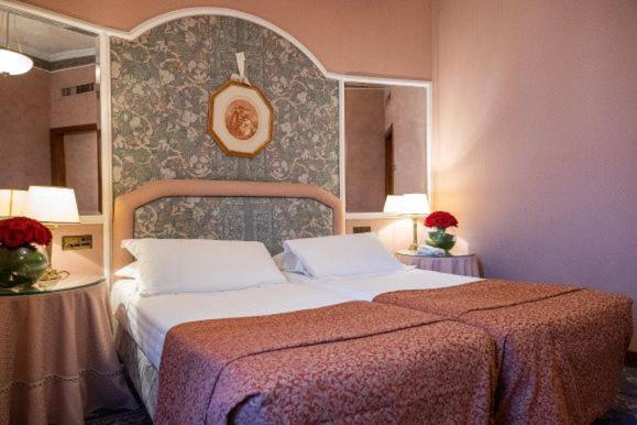 een slaapkamer met een bed en twee tafels met lampen bij Hotel Mecenate Palace in Rome