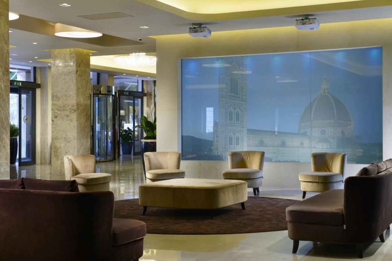 een lobby met stoelen en een grote afbeelding van een gebouw bij FH55 Grand Hotel Mediterraneo in Florence