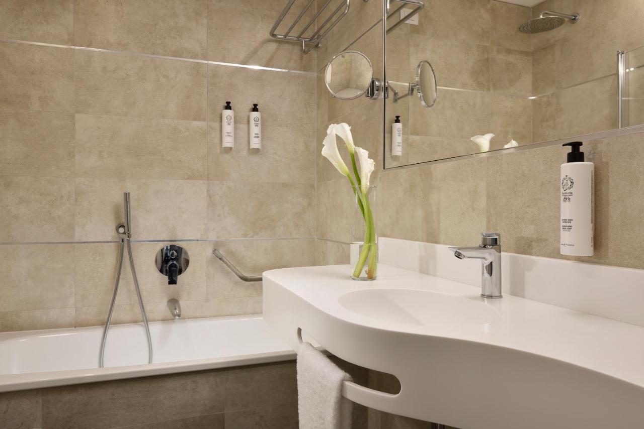 een badkamer met een wastafel en een vaas met een bloem bij FH55 Grand Hotel Mediterraneo in Florence