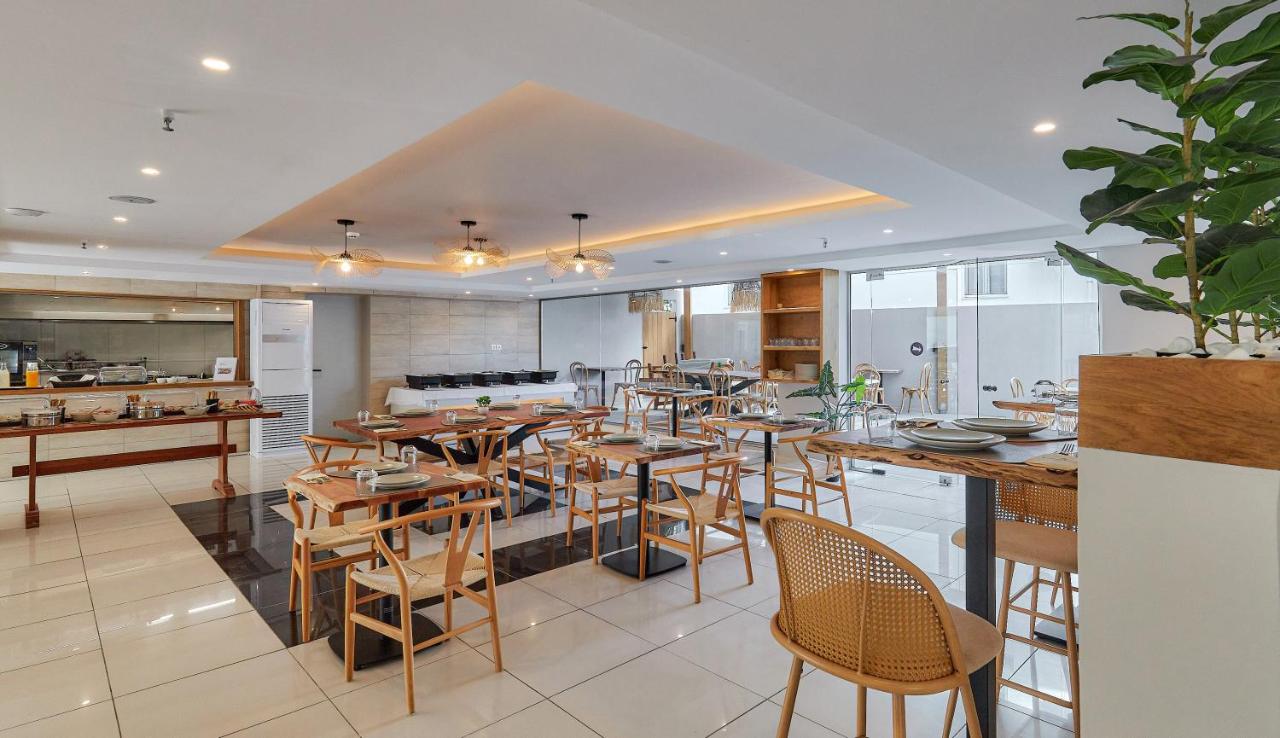 een eetkamer met tafels en stoelen en een keuken bij Lotus Rise Hotel - Adults Only in Chersonissos