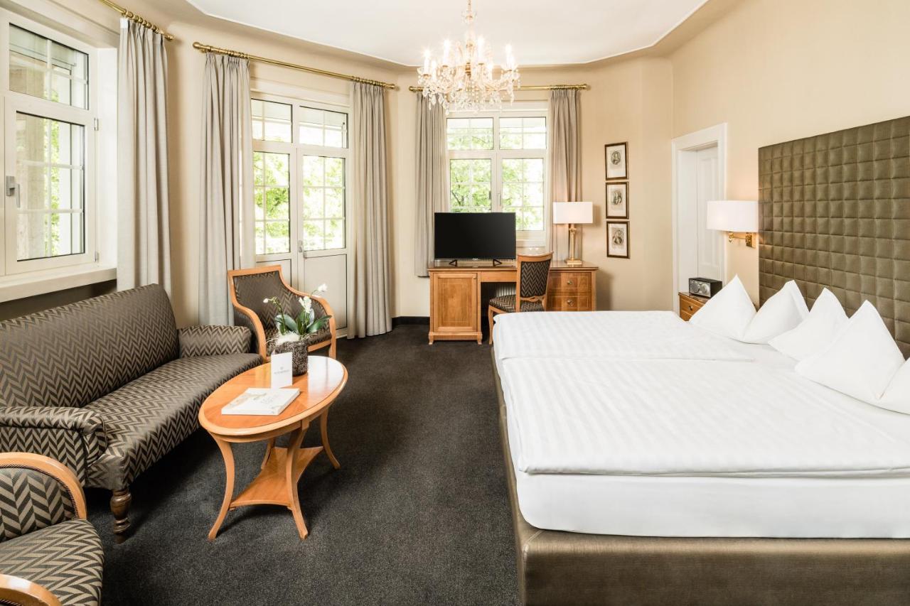 een hotelkamer met een groot bed en een bank bij Classic Hotel Meranerhof in Merano