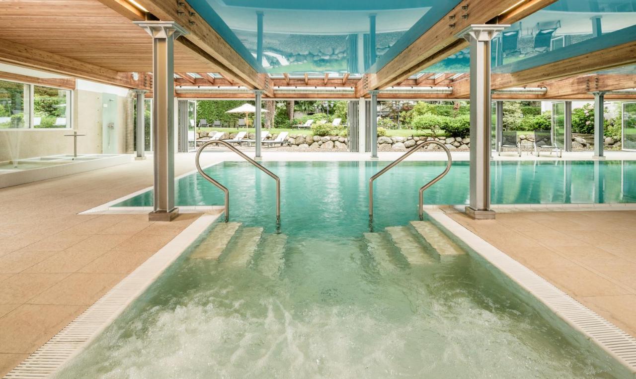 een overdekt zwembad met water in een gebouw bij Classic Hotel Meranerhof in Merano