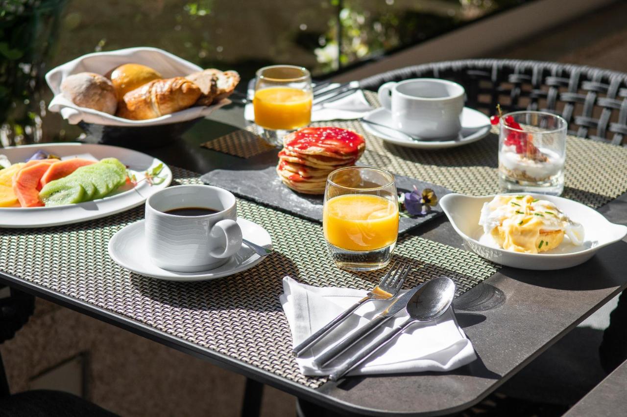 een tafel vol met borden ontbijtproducten en sinaasappelsap bij SANA Metropolitan Hotel in Lissabon
