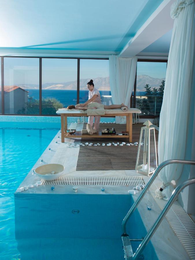 een man zit op een bankje naast een zwembad bij Miramare Resort & Spa in Agios Nikolaos