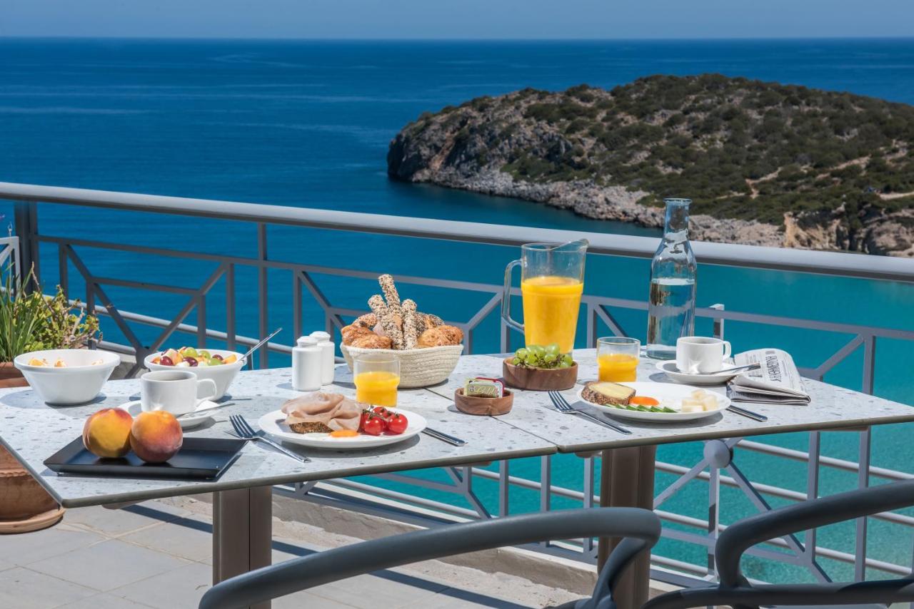 een tafel met eten en drinken op een balkon met uitzicht op de oceaan bij Mistral Mare Hotel in Istron