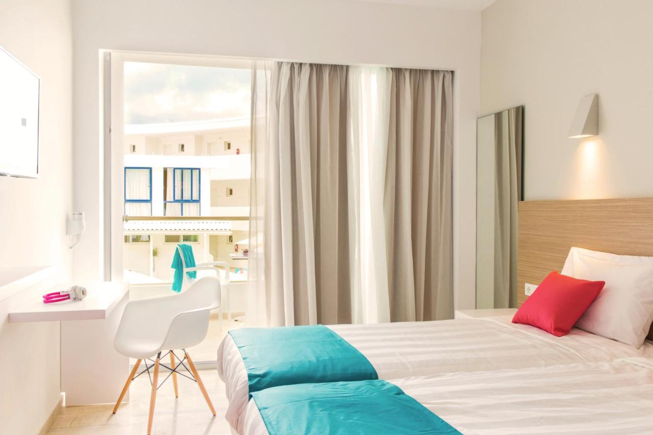 een slaapkamer met een bed, een bureau en een raam bij Nasos Hotel & Resort in Moraitika
