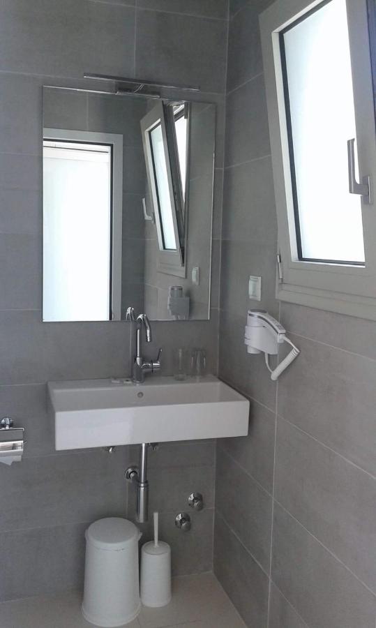een badkamer met een wastafel, een spiegel en een toilet. bij Nasos Hotel & Resort in Moraitika