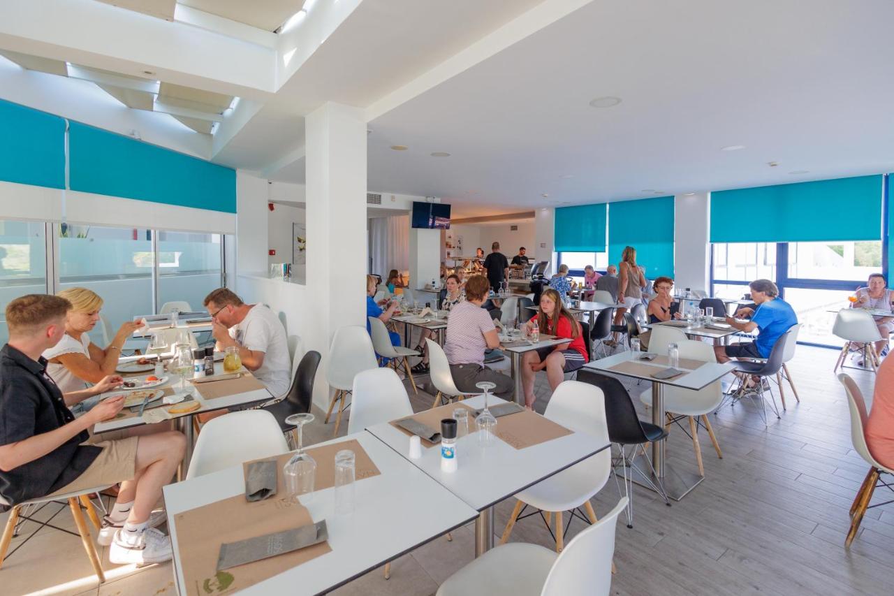 een groep mensen die aan tafels in een restaurant zitten bij Nasos Hotel & Resort in Moraitika
