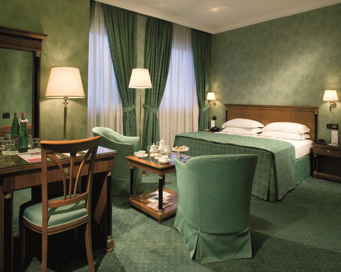 een hotelkamer met een bed, een tafel en stoelen bij Ramada by Wyndham Naples in Napels