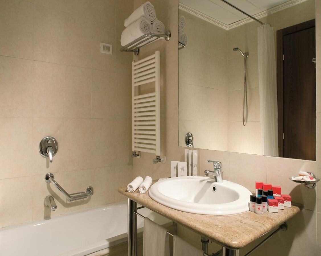 een badkamer met een wastafel, een badkuip en een spiegel bij Ramada by Wyndham Naples in Napels