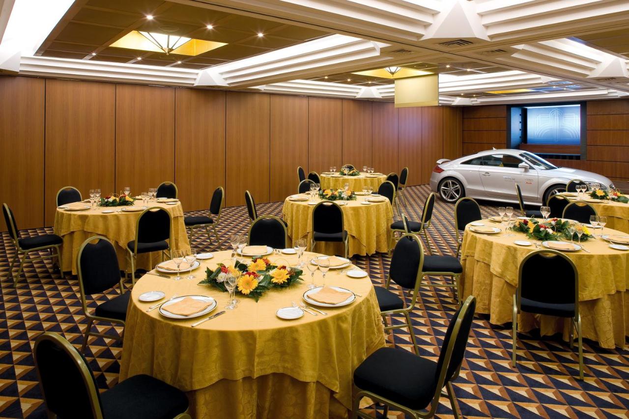 een feestzaal met tafels en stoelen en een auto bij Ramada by Wyndham Naples in Napels