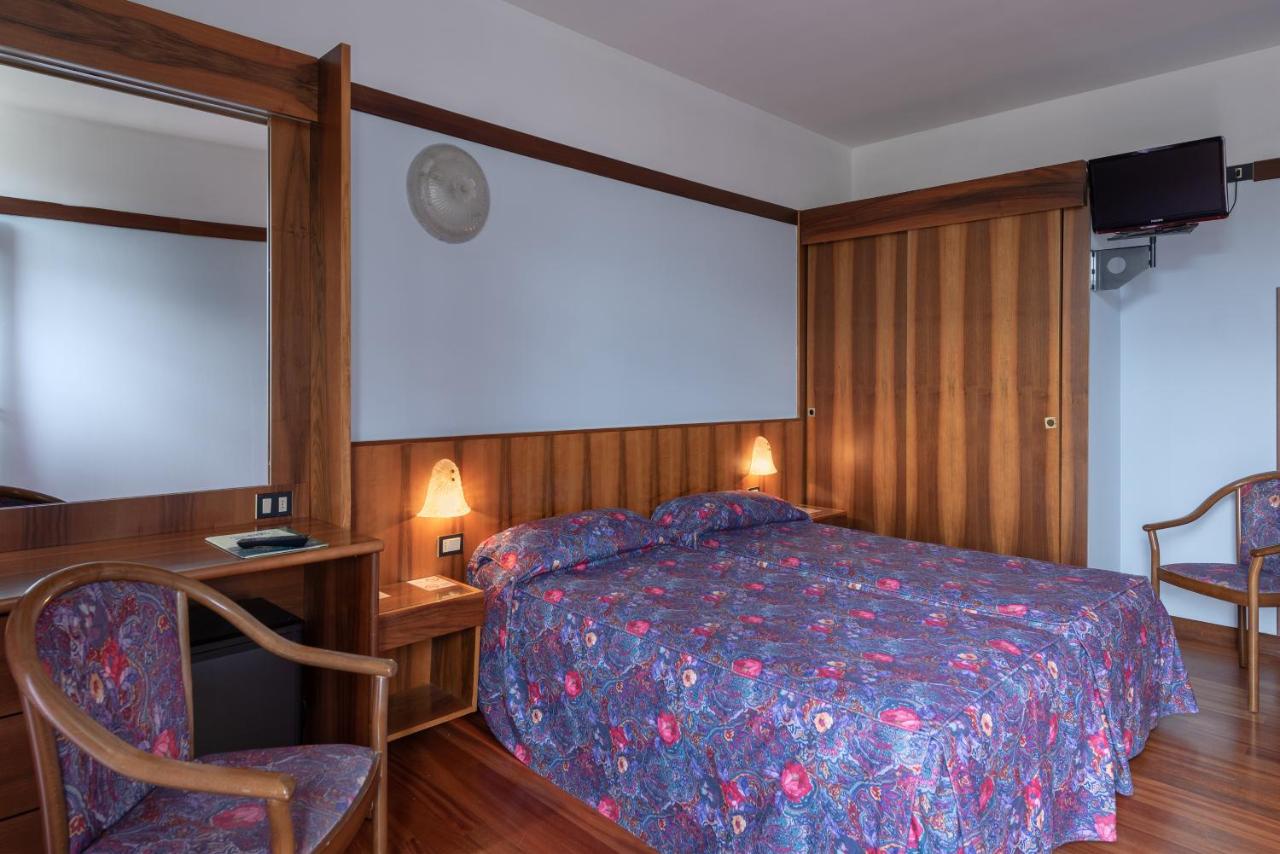 een slaapkamer met een bed, een bureau en een stoel bij Park Hotel Oasi in Garda