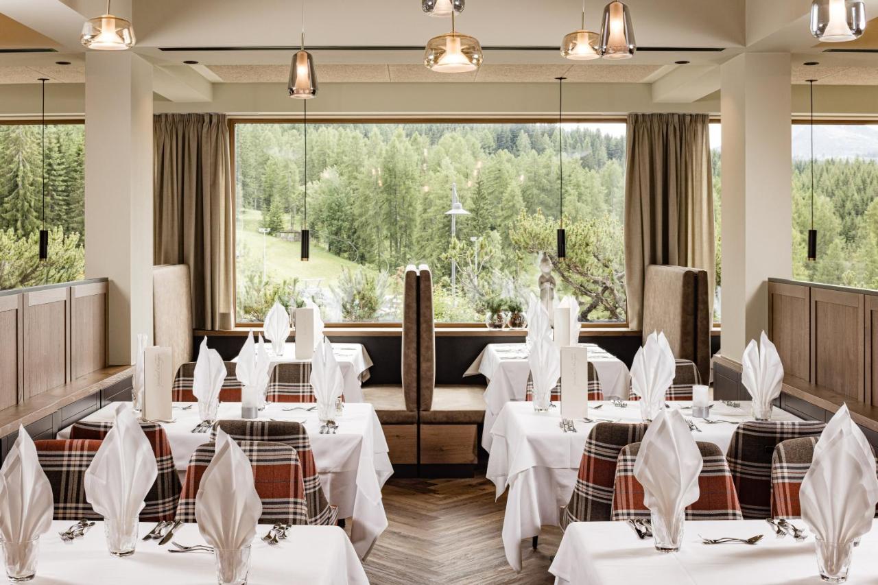 een restaurant met witte tafels en stoelen en grote ramen bij Sporthotel Obereggen in Obereggen +63 foto's
