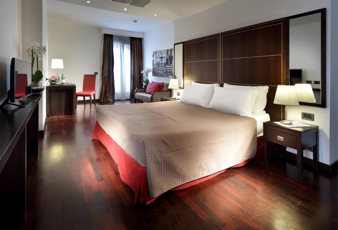 een hotelkamer met een groot bed en een woonkamer bij Exe International Palace in Rome
