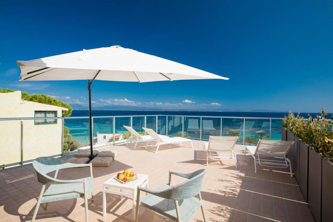 een terras met een tafel, stoelen en een parasol bij Lu' Hotel Maladroxia in SantʼAntìoco