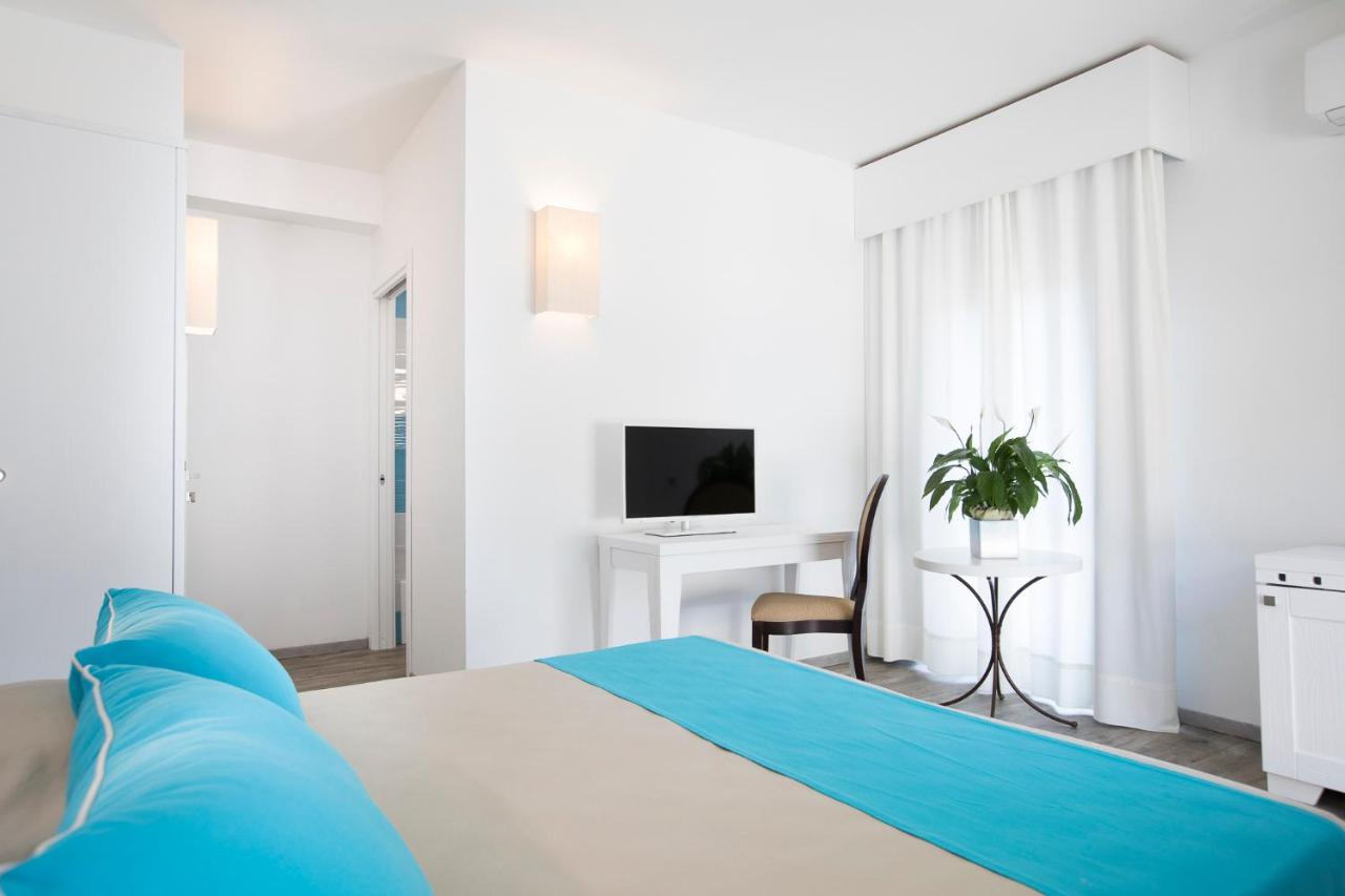 een witte slaapkamer met een bed en een bureau bij Lu' Hotel Maladroxia in SantʼAntìoco