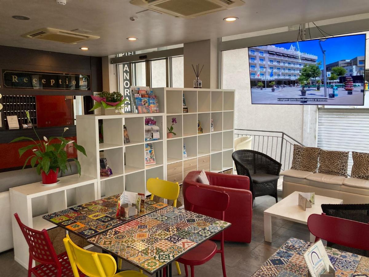 een restaurant met een tafel, stoelen en een tv bij Hotel Panorama in Lido di Jesolo