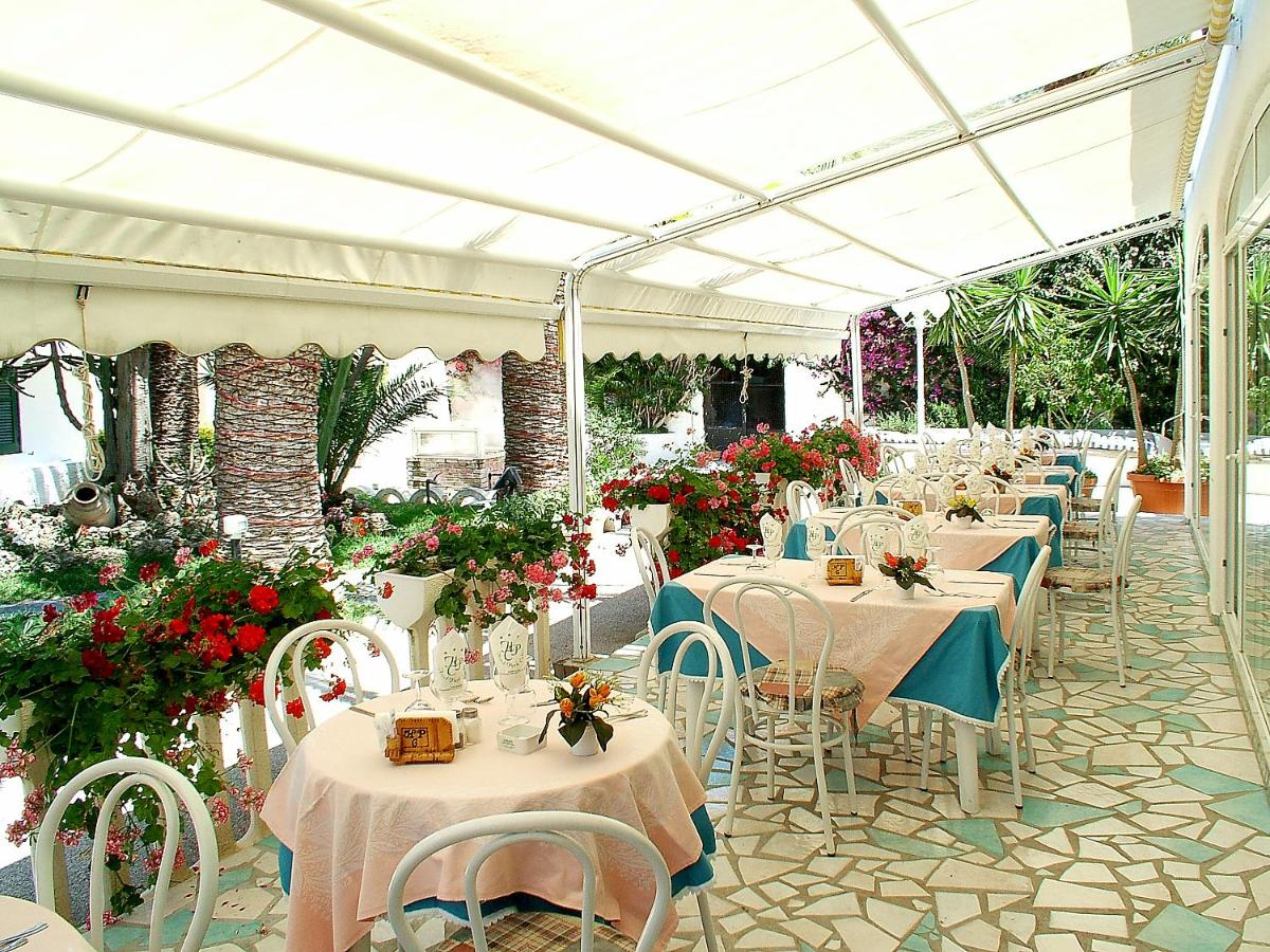 een rij tafels met witte stoelen en bloemen bij Hotel Park Calitto in Forio d'Ischia