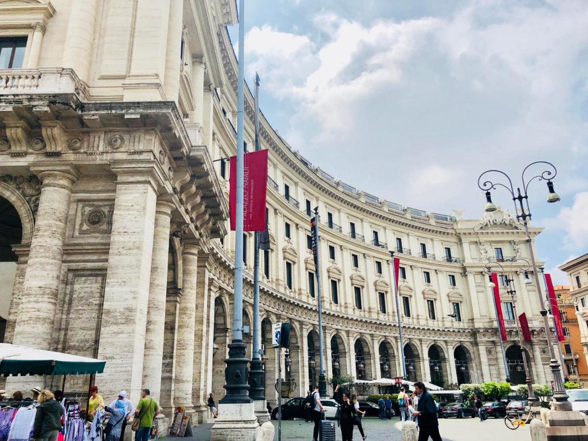een groot gebouw met mensen die ervoor lopen bij Hotel Paris in Rome