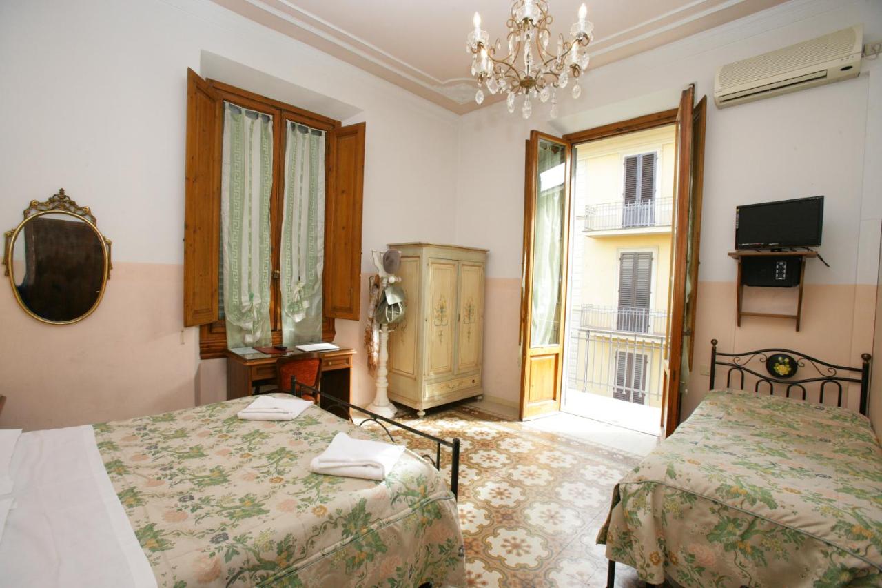 een slaapkamer met twee bedden, een televisie en een kroonluchter bij Hotel Desirèe in Florence