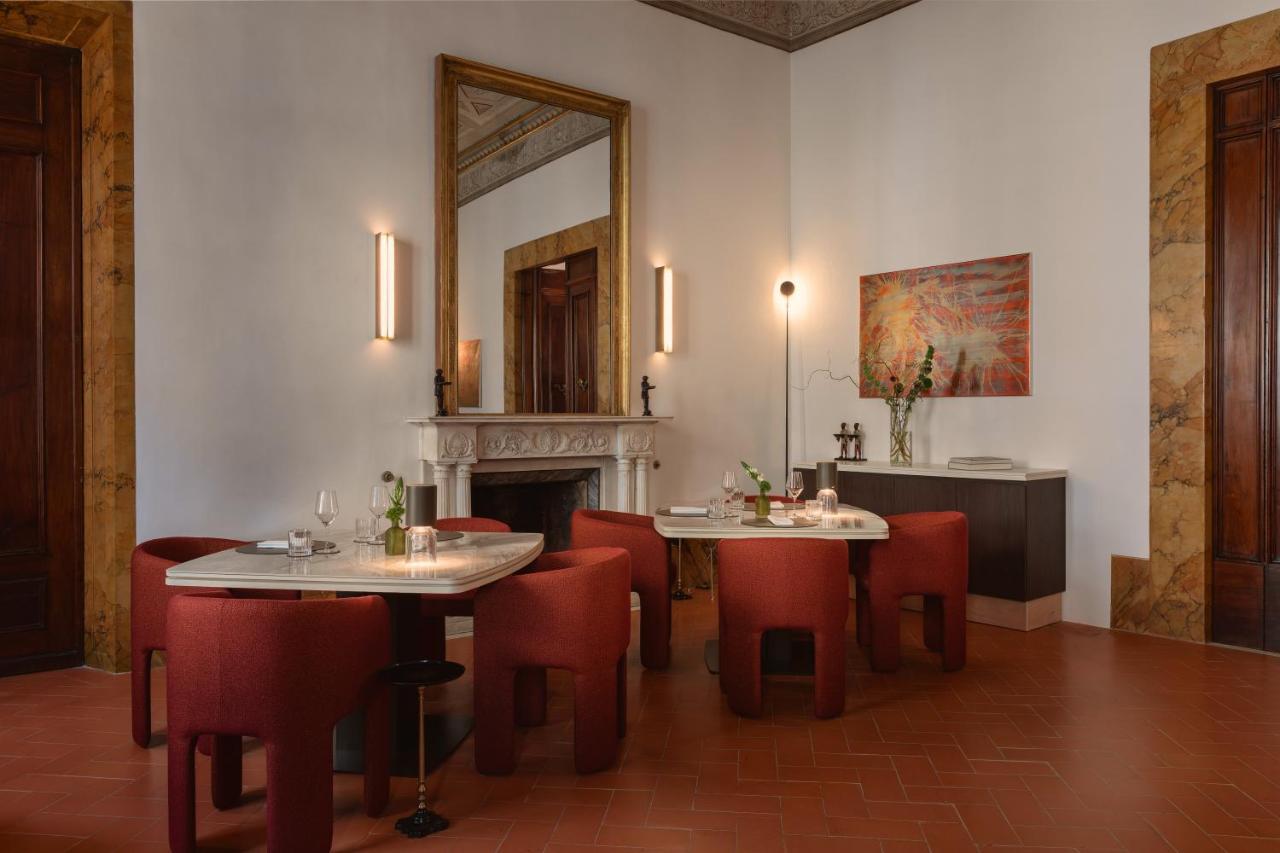 een eetkamer met twee tafels en stoelen en een open haard bij Palazzo Firenze by Baglioni Hotels & Resorts in Florence