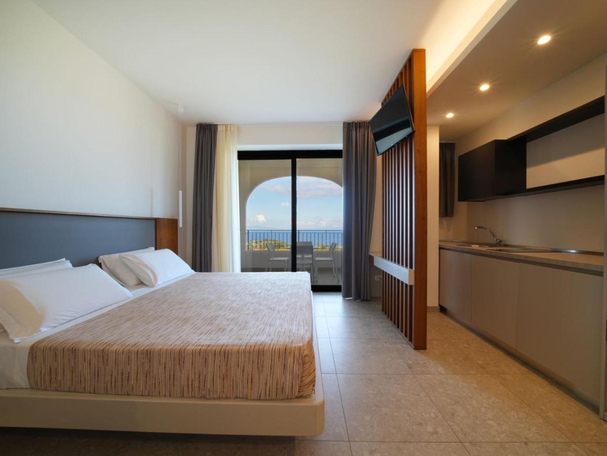 een slaapkamer met een bed en uitzicht op de oceaan bij LUZIA AGRIRESORT - Piscina Panoramica e vista Mare a Capo Vatica