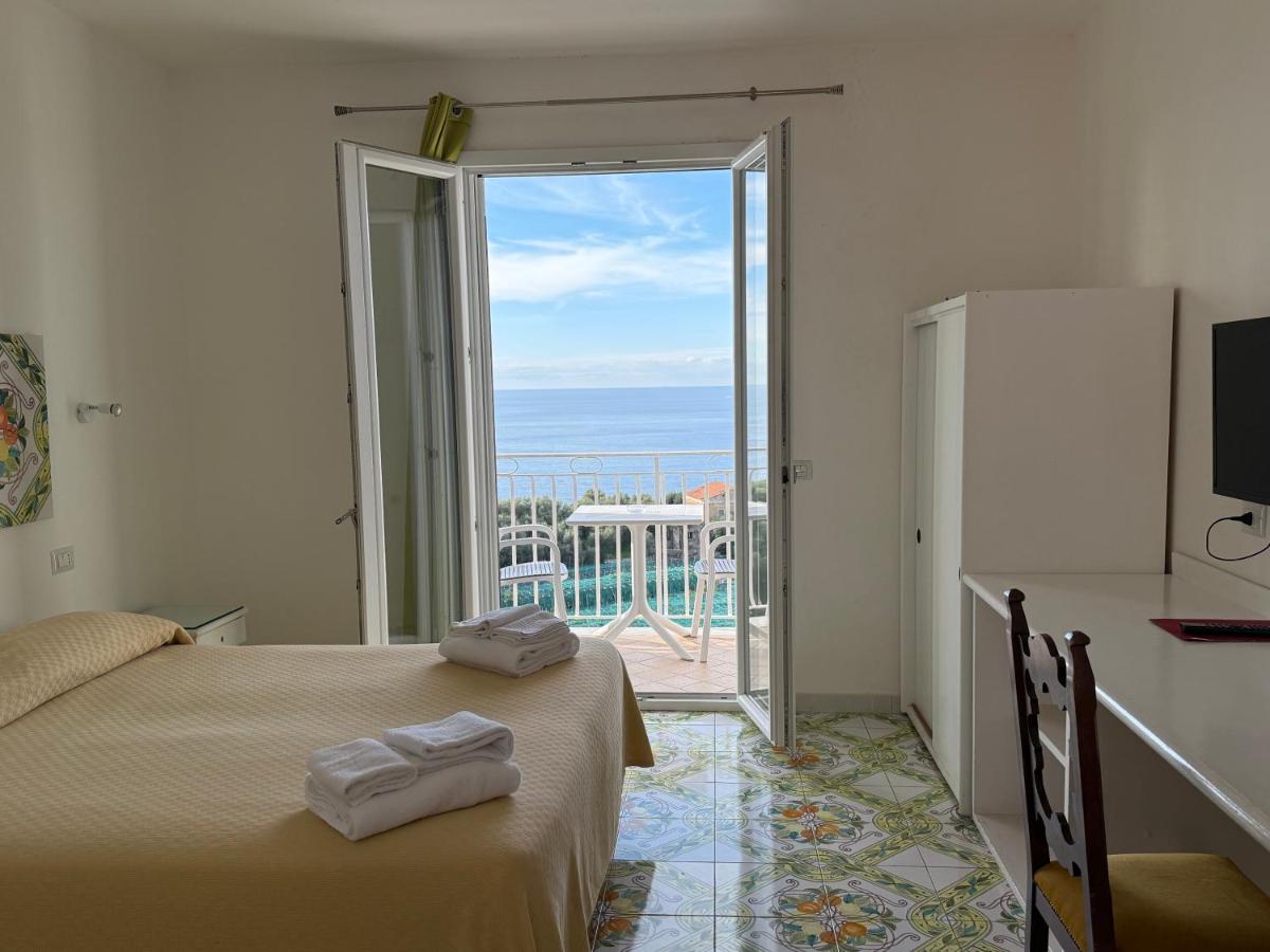 een kamer met twee bedden en een schuifdeur van glas bij Hotel Villa Pina Antico Francischiello in Massa Lubrense