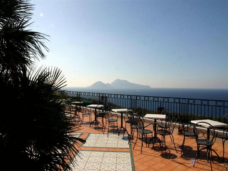 een groep tafels en stoelen op een terras met uitzicht op de oceaan bij Hotel Villa Pina Antico Francischiello in Massa 