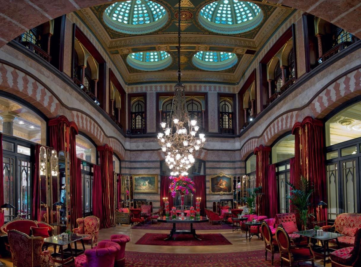 een grote kamer met een kroonluchter en tafels en stoelen bij Pera Palace Hotel in Istanbul