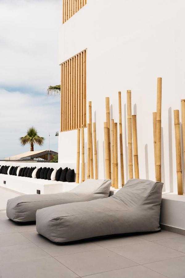 een kamer met twee bedden en een muur met houten palen bij Petradi Beach Lounge Hotel by GHH in Rethimnon