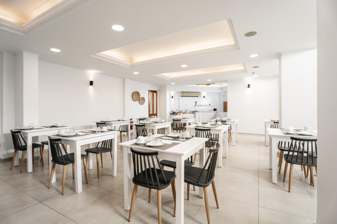 een eetkamer met witte tafels en zwarte stoelen bij Petradi Beach Lounge Hotel by GHH in Rethimnon