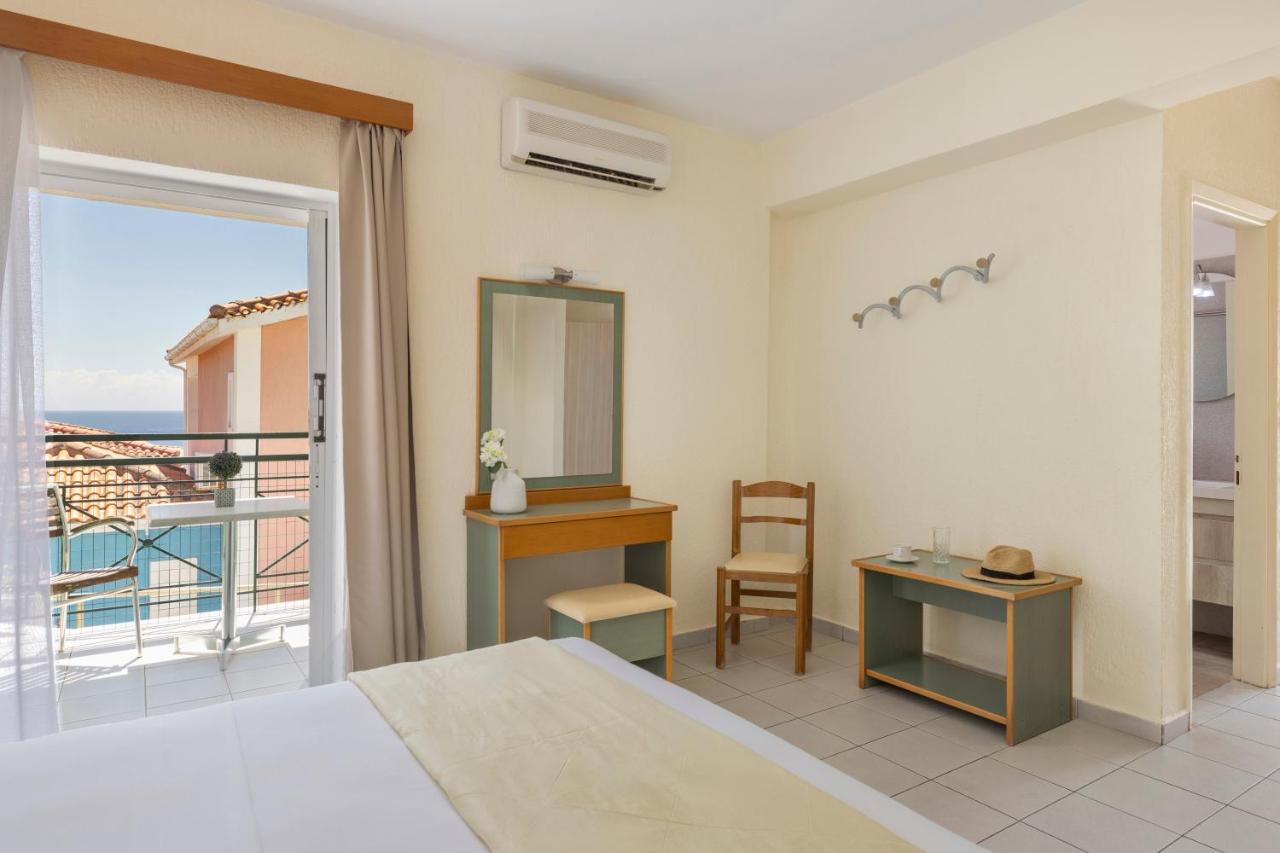 een slaapkamer met een bed en uitzicht op de oceaan bij Porto Skala Village Hotel in Skála Kefalonias
