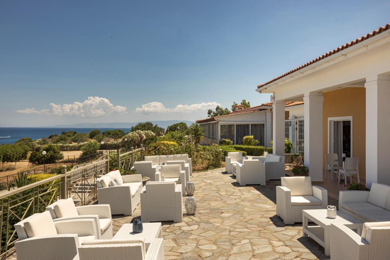 een terras met witte stoelen en uitzicht op de oceaan bij Porto Skala Village Hotel in Skála Kefalonias