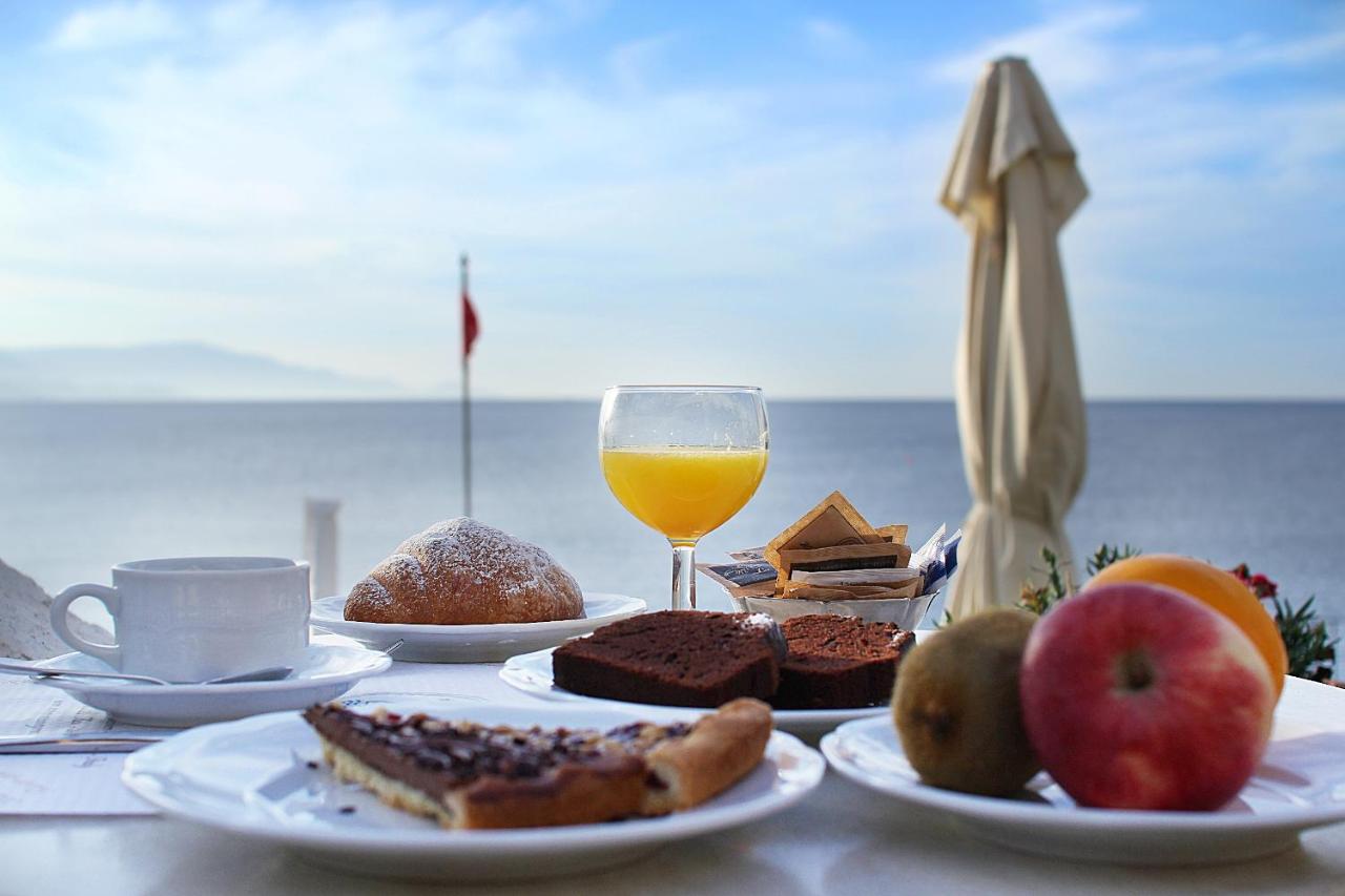 een tafel met borden vol eten en een glas sinaasappelsap bij Hotel Punta Negra in Alghero