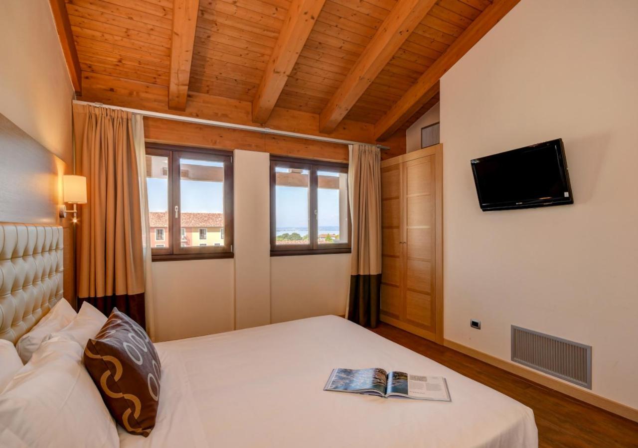 een slaapkamer met een bed waarop een boek ligt bij TH Lazise - Hotel Parchi Del Garda in Lazise