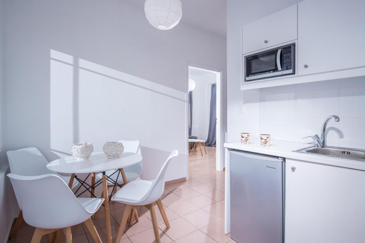een witte keuken met een tafel en witte stoelen bij W Suites by Estia in Stalida