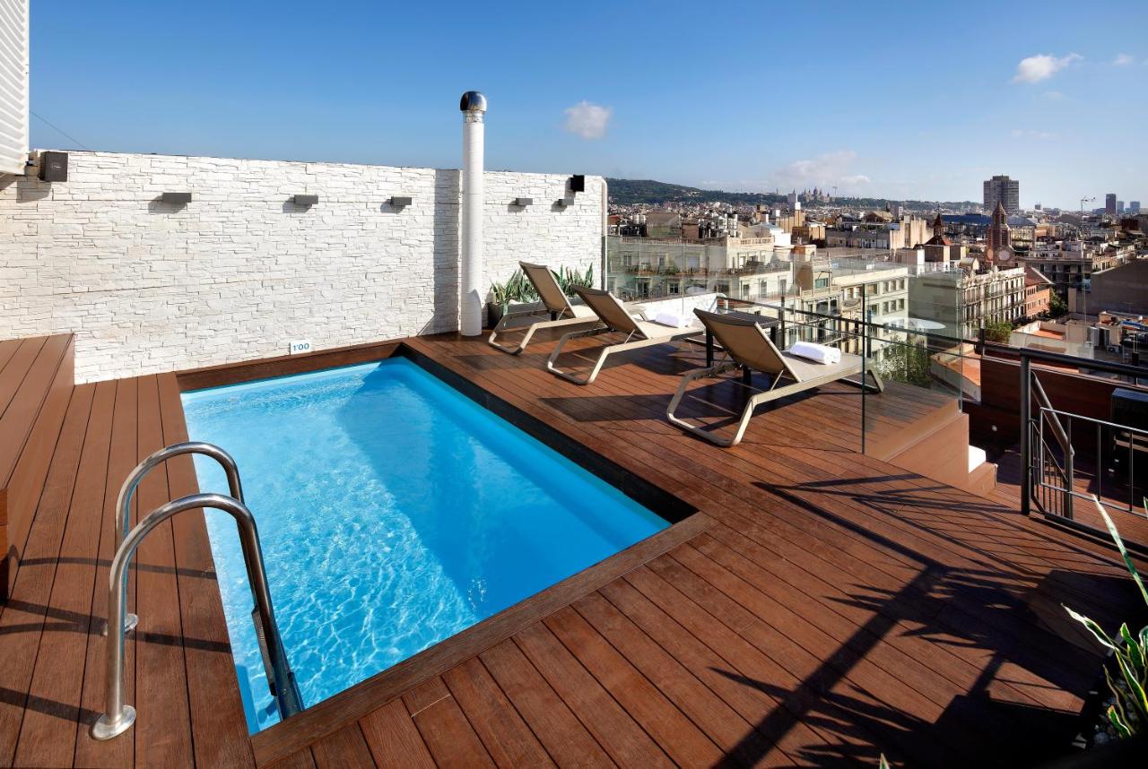 een dakterras met een zwembad op een gebouw bij HCC Regente in Barcelona