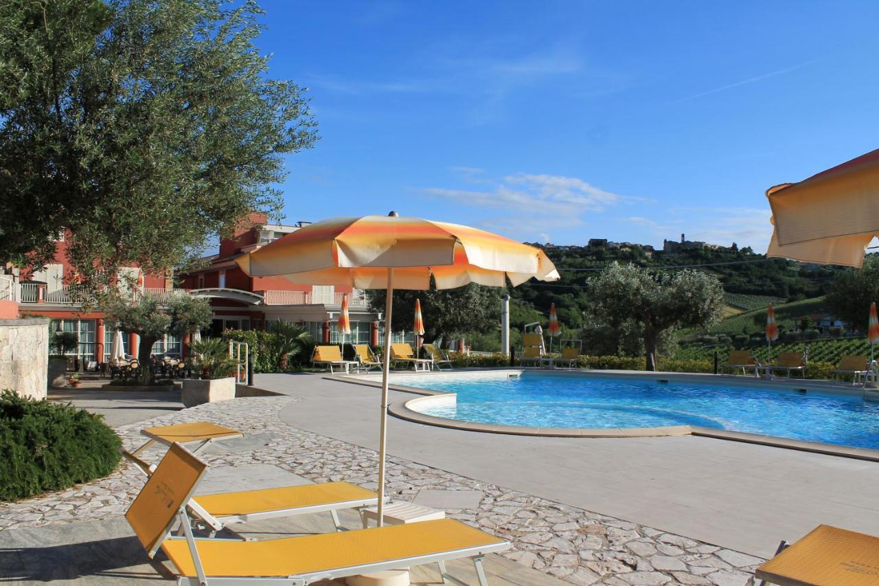 een zwembad met een parasol, stoelen en een tafel. bij Il Parco Sul Mare Resort & SPA in Tortoreto Lido