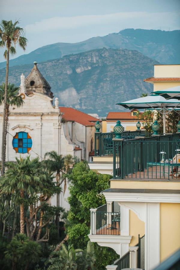 een groep gebouwen met palmbomen en een berg bij Grand Hotel La Favorita in Sorrento
