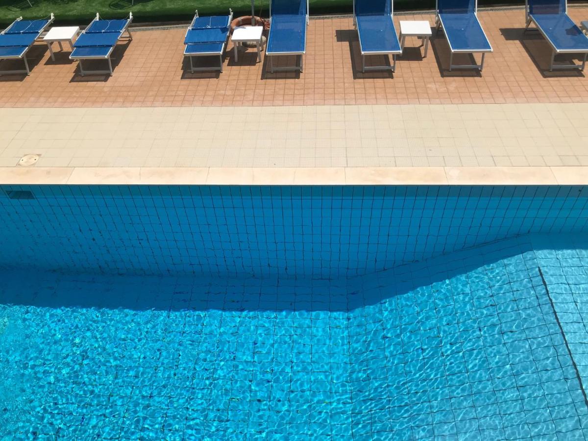 een zwembad met blauwe ligstoelen ernaast bij Hotel Apogeo - Breakfast Experience in Rimini