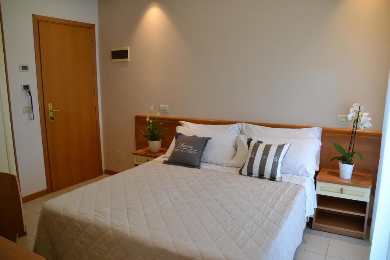 een slaapkamer met een bed met witte lakens en kussens bij Hotel Apogeo - Breakfast Experience in Rimini